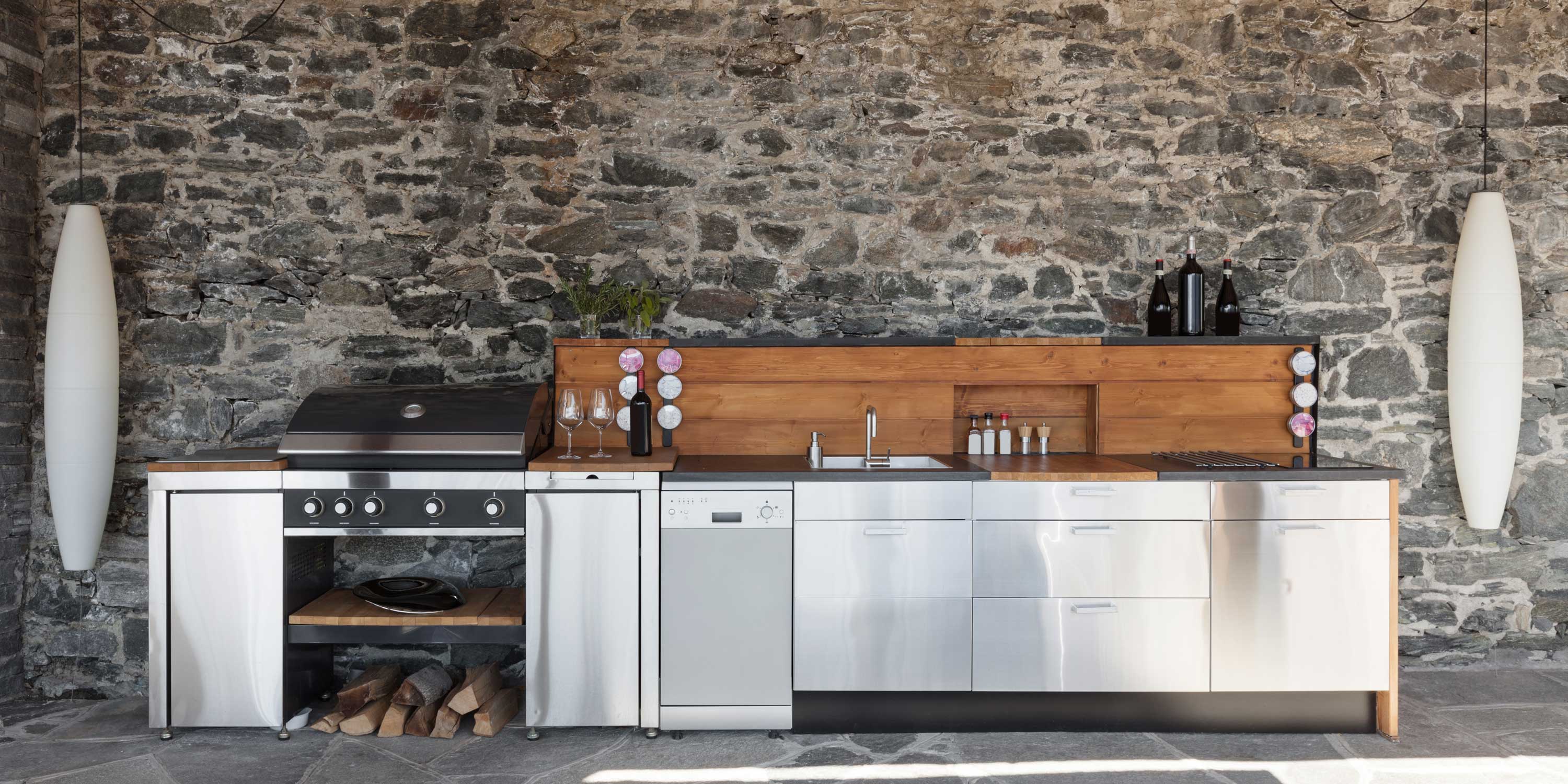 Outdoor kitchen, silver appliances, wooden background, stone wall